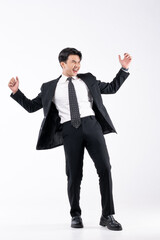 A man in a black suit and tie stands in front of a white background