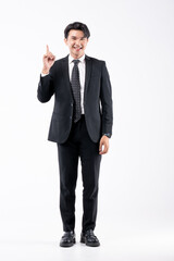 A man in a black suit and tie stands in front of a white background
