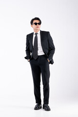 A man in a black suit and tie stands in front of a white background
