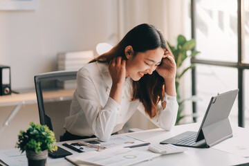Young Asian businesswoman working on laptop computer, stressed has a headache and thinks hard from...