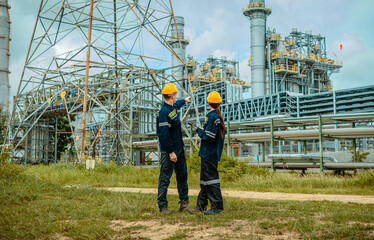 Engineers discussing project details at an industrial facility in a rural area during daylight hours