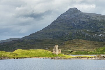 Ruins of Ardvreck Castle on a peninsula in the lake of Loch Assynt, in front of the 764m mountain...