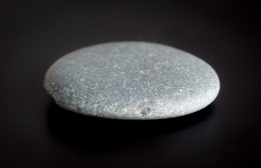 A gray rock is sitting on a black surface