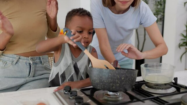 Child boy cooking some food with family in the kitchen