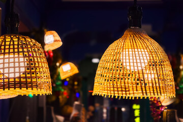 Obraz premium Decorating hanging lantern lights lamp shade in handcraft wicker made from bamboo. Close-up lampshade in shape of basket from natural material in cafe interior. Cozy lightning decor of rattan celling.