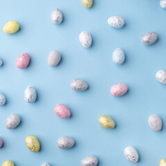 Festive Easter background. Multicolored Easter eggs on a blue table. Top view.