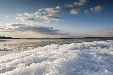 Sunlight with moody clouds, stacked ice floes on the shore of Reichenau Island, Baden-Wuerttemberg, Germany, Europe