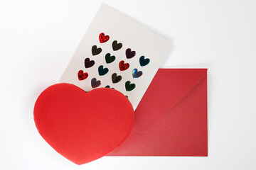 A red heart, a Valentine's Day card with colorful heart stickers, and a red envelope on a white background, perfect for love-themed imagery.