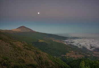 Fototapeta premium Night view of trade wind clouds over Orotava valley with Pico del Teide in front of sunrise, behind La Palma, Teide National Park, Tenerife, Canary Islands, Spain, Europe