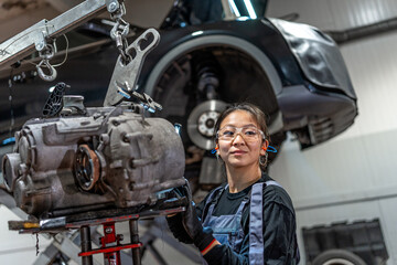 Female mechanic fixing gearbox in auto repair shop
