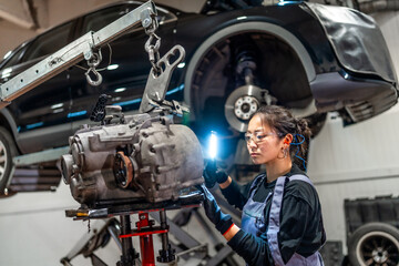 Female mechanic inspecting gearbox in auto repair shop