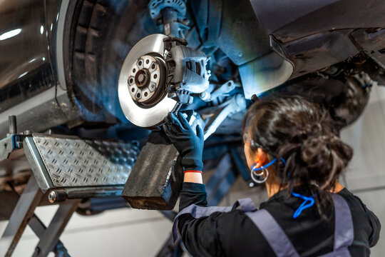 Female mechanic fixing car brakes in auto repair shop