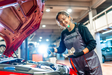 Female mechanic checking oil level in car engine at garage