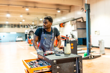 Fototapeta premium Mechanic working in auto repair shop with tools and equipment
