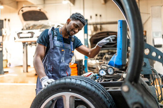 Mechanic changing car tire using digital tyre changer in auto repair shop