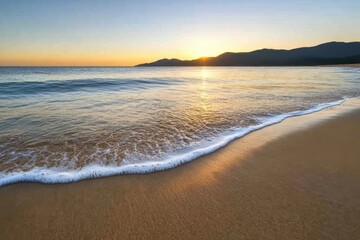 Obraz premium A calm beach with soft waves and a sunrise reflecting on wet sand, creating a tranquil and serene atmosphere
