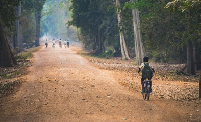 Obraz premium Local children ride bicycles, way to school, Angkor Archaeological Park, Siem Reap Province, Cambodia, Asia