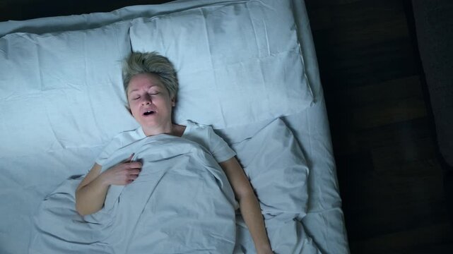 Portrait of sleeping man in dream suffering from nightmares in bed, top view.