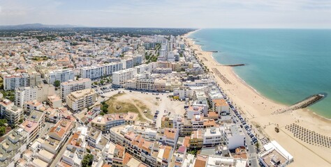 White architecture and blue Atlantic ocean in Quarteira resort during sunny day, Algarve, Portugal,...