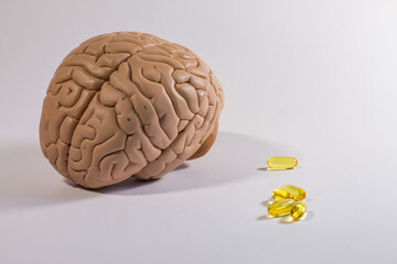 Educational model of the human brain with pills, in the background brain waves from...