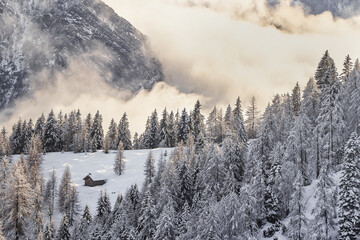 Sun rays behind the snowy chalet, Val Brembana, Lombardy