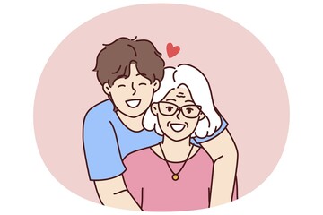 Noble guy teenager hugging elderly grandmother showing love and care for ancestors and communicating with family. Happy retired woman near caring son spending time in family atmosphere