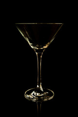 Empty martini glass on a black background with reflection. Studio shot