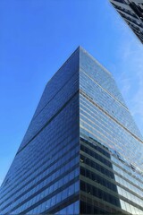 Office building with a full glass facade at daylight with a blue sky, AI generated