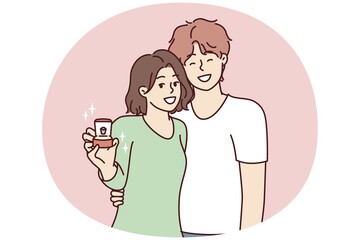 Young couple of man and woman stand in embrace and look at camera showing box with wedding ring. Bride and groom in casual clothes after proposal for joint family life. Flat vector illustration
