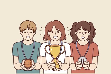 Children with trophies for winning school olympiads or competitions rejoice in awards for leadership positions. Girl with winner cup stands near classmates with medals out for winning competition