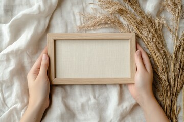 Hands holding a blank wooden frame on fabric