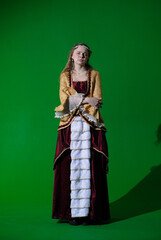 Fototapeta premium Woman in ancient outfit on chroma key green screen background. Female in renaissance dress with negative doubting face looking at camera and posing.