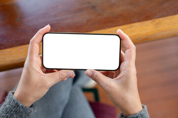 A top view of a woman holds a smartphone in a horizontal positive as she watching videos.