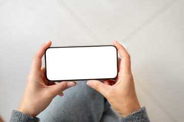 A top view of a woman holds a smartphone in a horizontal positive as she watching videos, indoors.