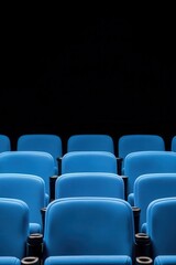 Obraz premium Empty blue theater seats in a dark space, awaiting an audience.