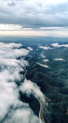 Fototapeta premium Aerial view of winding road through cloudy mountains.