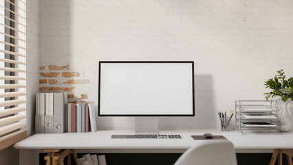A computer and decorative items placed on a white desk against a white brick wall.