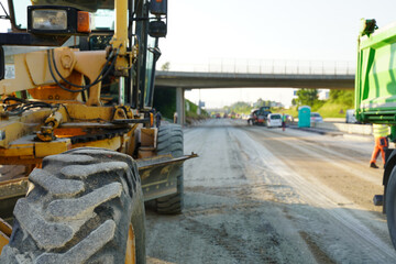 Fototapeta premium Road construction machine leveling and smoothing the gravel base to create a stable foundation for new asphalt paving