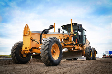 Road construction machine leveling and smoothing the gravel base to create a stable foundation for new asphalt paving