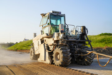 Fototapeta premium Heavy-duty asphalt recycler on a highway construction site, processing old pavement to create a stable foundation for a new asphalt layer