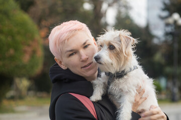 Cute woman having fun playing with pet dog outdoors