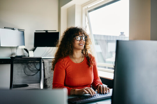 Woman in Red Shirt Working on Computer in Bright Modern Office
