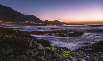 Rocky coast and sea at sunset, backlit place Bajamar and volcano Pico del Teide, Punta del Hidalgo,...
