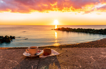 cup of coffee or tea with croissant on a morning embarkment beach with blue sea and beautiful...