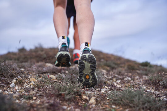 Close-up of hikers&rsquo; feet walking uphill on a rugged trail with hiking shoes