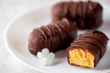 Vegan cheesecake candy bar with chocolate glaze from millet and dried apricots, chocolate syrok on a plate, closeup. Selective focus.