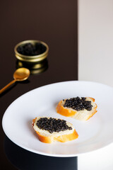 Sandwiches with black caviar on black and white table. Sturgeon caviar. Vertical orientation.