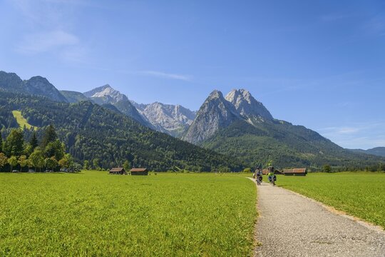Cyclists on the Via Claudia Augusta long-distance cycle path, in the back Zugspitze, mountain landscape, Alpine crossing, Tegernauweg, near Grainau, Garmisch-Partenkirchen, Upper Bavaria, Bavaria, Germany, Europe