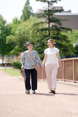 A park with good atmosphere with canal in Toyama Prefecture. Old woman in her 90s and Japanese woman in her thirties are walking around the park.