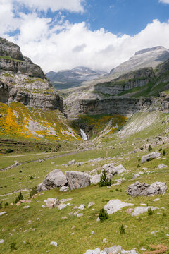 A breathtaking view of a lush mountain valley with a waterfall in Ordesa y Monte Perdido National Park, Spain. A perfect destination for trekking, hiking, mountaineering, and summer outdoor adventures